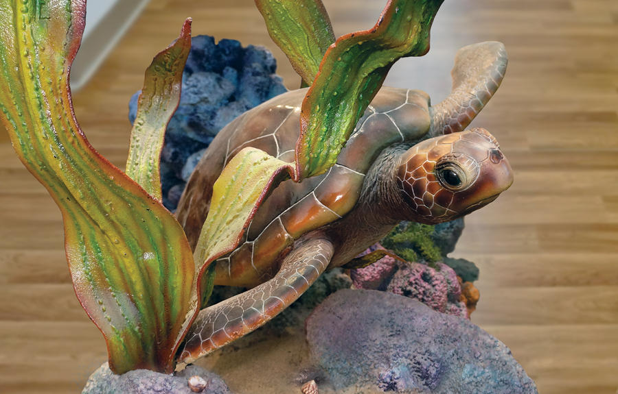Closeup of a realistic sculpted turtle surrounded by seaweed and coral