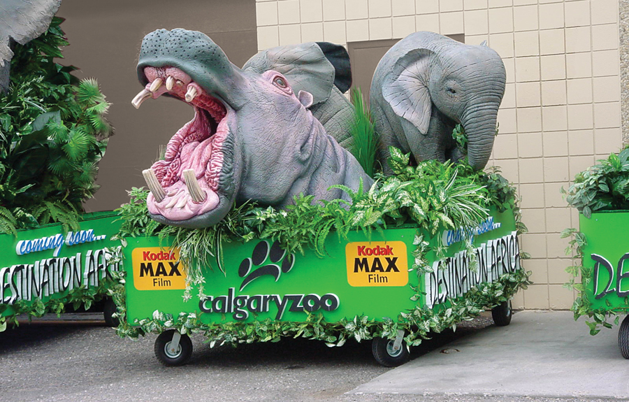 Parade floats for a zoo featuring  sculpted african animals and foliage