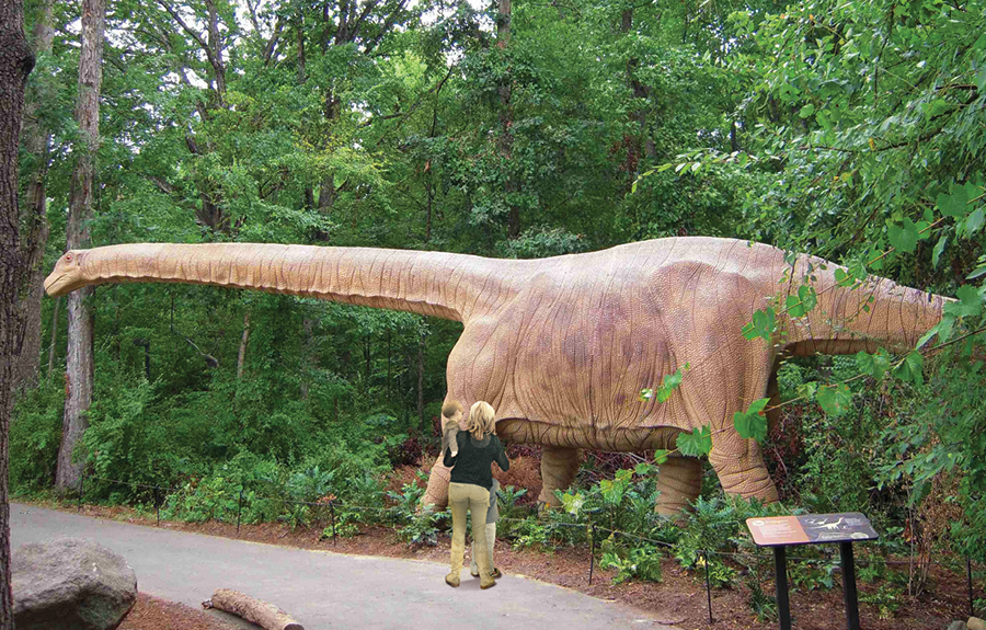 Realistic statue of giant dinosaur in an outdoor zoo exhibit