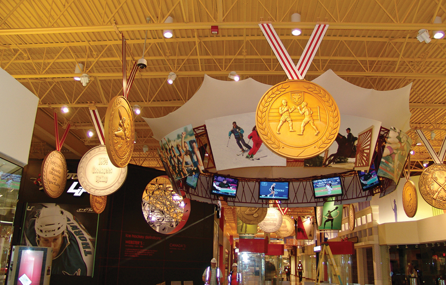 Large foam props of sports gold medals on display in a mall resting area